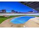 Backyard with a pool surrounded by green grass, and a tanning chair at 8645 Edmond St, Las Vegas, NV 89139