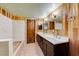 Bathroom with double sink vanity, wood paneling, unique mirrors and decorative towel ring at 9010 W Lone Mountain Rd, Las Vegas, NV 89129