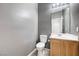 Stylish half bathroom showcasing a gray accent wall, tiled floors, and a wood vanity with modern fixtures at 7506 Village Mist Ln, Las Vegas, NV 89113