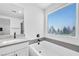 Modern bathroom featuring a soaking tub with quartz countertops and a large window at 10214 Natural Anchor St, Las Vegas, NV 89166