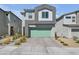 Contemporary two-story home featuring a gray facade, green garage door, and well-maintained landscaping at 10214 Natural Anchor St, Las Vegas, NV 89166