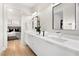 Modern bathroom features double sinks with sleek white cabinets and a view to the bedroom at 10261 Largo Sassetta Ct, Las Vegas, NV 89135