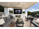 Relaxing outdoor living space featuring a fireplace, TV, and grill, perfect for entertaining and leisure at 10261 Largo Sassetta Ct, Las Vegas, NV 89135