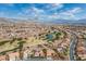Expansive aerial view of a community with a golf course, serene pond, and stunning mountain backdrop at 10524 Longwood Dr, Las Vegas, NV 89134