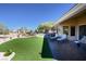 Spacious backyard featuring a covered patio, lounge chairs, an outdoor kitchen and lush synthetic grass at 10524 Longwood Dr, Las Vegas, NV 89134