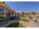 Outdoor patio with shade umbrella, table, and lush landscaping with a distant mountain view at 10524 Longwood Dr, Las Vegas, NV 89134