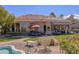 Back exterior view showing covered patio, outdoor kitchen, manicured landscaping and a glimpse of the pool at 10524 Longwood Dr, Las Vegas, NV 89134