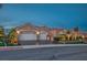 Charming single-story home featuring a three-car garage, desert landscaping, and a classic stucco facade at dusk at 10524 Longwood Dr, Las Vegas, NV 89134