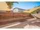 Desert landscaped backyard featuring a block wall with mature trees and a covered patio area at 11091 Parete Ct, Las Vegas, NV 89141