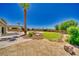 Backyard featuring lush green grass, a swimming pool, a covered patio, mature landscaping, and desert vegetation at 1131 China St, Pahrump, NV 89048