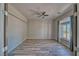 A neutral-toned bedroom with wood floors, a ceiling fan, and a large window with curtains at 1131 China St, Pahrump, NV 89048