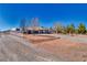 Attractive single-story home situated on a desert landscape, enhanced with a white fence, mature trees, and a long driveway at 1131 China St, Pahrump, NV 89048