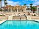 Community pool area with multiple lounge chairs and tables, a covered pergola, and a clubhouse at 1964 Las Palmas Ln # 244, Laughlin, NV 89029