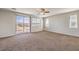 Bright bedroom featuring a ceiling fan, neutral carpet, and sliding door to the outdoor balcony at 228 Via Vallisneri, Henderson, NV 89011