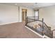 Upstairs loft area with staircase and wood railing featuring neutral colored carpet in the living area at 228 Via Vallisneri, Henderson, NV 89011