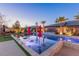 Backyard pool with tanning deck, lounge chairs, umbrellas, colorful accent lighting, and well manicured yard at 274 Chartan Ave, Las Vegas, NV 89183