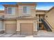 Two-story building with a beige exterior, tile roof, garages, and stairway at 4685 Apulia Dr # 202, North Las Vegas, NV 89084