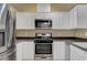 Well-lit kitchen with white cabinetry, stainless steel appliances, and dark countertops at 4685 Apulia Dr # 202, North Las Vegas, NV 89084