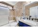 Bathroom showcasing a tub-shower combo with decorative tile surround, and a blue vanity with a granite countertop at 5049 Hibbetts Ct, Las Vegas, NV 89103