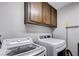 A well-equipped laundry room with updated appliances, cabinet storage, and a wall-mounted mop and broom holder at 5049 Hibbetts Ct, Las Vegas, NV 89103
