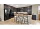 Modern kitchen with dark cabinetry, a granite-topped island with seating, and open layout to dining and living areas at 5614 Bishop Flowers St, Las Vegas, NV 89130