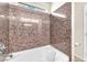 Bathroom boasts a tub with a unique shower, granite-look tile surround, and neutral paint at 5671 Camilla Cellars Ct, Las Vegas, NV 89141