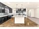 Modern kitchen features dark cabinets, a stone backsplash, and a large island with pendant lights at 5671 Camilla Cellars Ct, Las Vegas, NV 89141