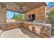 Outdoor kitchen with built-in grill, TV, and stone accents at 5671 Camilla Cellars Ct, Las Vegas, NV 89141