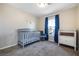 Bedroom featuring a gray crib, window with curtains, and functional changing table at 6745 Jackson Junction St, Las Vegas, NV 89149