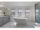 Bright bathroom featuring a soaking tub, a gray vanity with marble countertop, and a glass-enclosed shower at 6909 Forest Gate St, North Las Vegas, NV 89084
