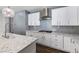 Modern kitchen with white cabinets, gray backsplash, stainless steel appliances, and granite countertops at 6909 Forest Gate St, North Las Vegas, NV 89084