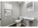 Clean powder room featuring a pedestal sink, white toilet, and natural light from the window at 6909 Forest Gate St, North Las Vegas, NV 89084
