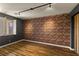 Contemporary bedroom with hardwood flooring, brick accent wall, and modern track lighting at 7180 White Bloom Ave, Las Vegas, NV 89117