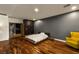 Modern bedroom with wood floors, brick accent wall, and a yellow lounge chair at 7180 White Bloom Ave, Las Vegas, NV 89117