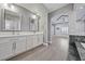 This bathroom features double sinks with white cabinets and gray wood floors leading to the main bedroom at 9090 Josepine St, Pahrump, NV 89048