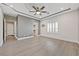 This main bedroom features tray ceilings, gray wood floors, plantation shutters, and a modern light fixture at 9090 Josepine St, Pahrump, NV 89048