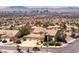 Aerial view of a desert home featuring a three-car garage, landscaping, and desert surroundings at 979 Evening Dew Dr, Las Vegas, NV 89110