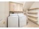 Bright laundry room features a washer and dryer, plenty of storage with shelves, and neutral tiling at 979 Evening Dew Dr, Las Vegas, NV 89110