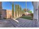 Private backyard with tiled patio, low-maintenance turf and mature Cypress trees at 10955 Sospel Pl, Las Vegas, NV 89141