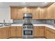 Modern kitchen featuring stainless steel appliances, granite countertops, and wood cabinets at 10955 Sospel Pl, Las Vegas, NV 89141