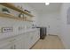 Bright laundry room featuring custom cabinets with gold hardware, shelving, and modern appliances at 1660 W Princeton Cir, Pahrump, NV 89060