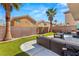 A backyard featuring a patio with outdoor seating, artificial turf, mature palm trees and block wall fence at 232 Dog Leg Dr, Las Vegas, NV 89148