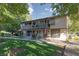 Two-story townhome with a balcony, green lawn, and mature shade trees on a sunny day at 3189 Pinehurst Dr # B, Las Vegas, NV 89109