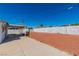 Wide view of the backyard with red rock landscaping, white fencing, and a covered patio at 3212 Hickey Ave, North Las Vegas, NV 89030