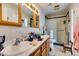 Bright bathroom features wood cabinets, updated lighting, and shower with glass door at 4476 Oakhill Cir, Las Vegas, NV 89121