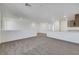 Spacious living room with neutral carpet, white walls and trim and a partial view of the kitchen at 4561 Woolcomber St, Las Vegas, NV 89115