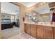 A view of the main bathroom showcasing double sinks, vanity lighting, tile flooring, with a view of the main bedroom at 6470 Little Harbor Ct, Las Vegas, NV 89141