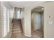 Hallway featuring staircase, shuttered window, arched doorway, and neutral-toned carpet at 6773 Goose Watch Ct, Las Vegas, NV 89139