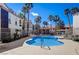 Community pool area surrounded by palm trees and nearby residential units on a sunny day at 700 Carnegie St # 3214, Henderson, NV 89052