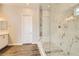 Elegant bathroom with a marble shower, white cabinets, and wood-look floors at 728 Omaggio Pl, Henderson, NV 89011